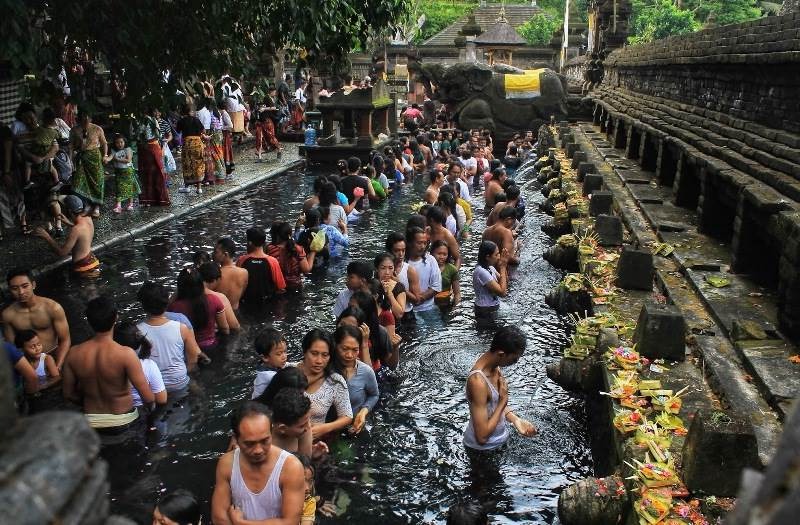 Tirta Empul Temple's bathing pool is crowded with visitors who want to melukat